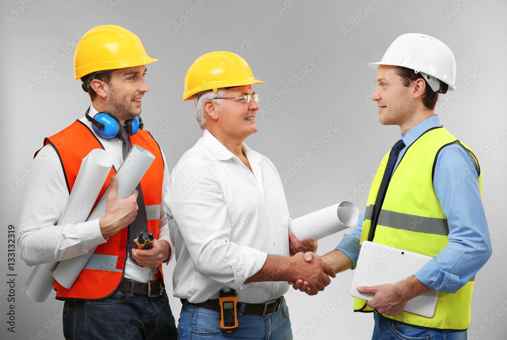 Senior engineer and workers on light background Senior engineer and workers on light background