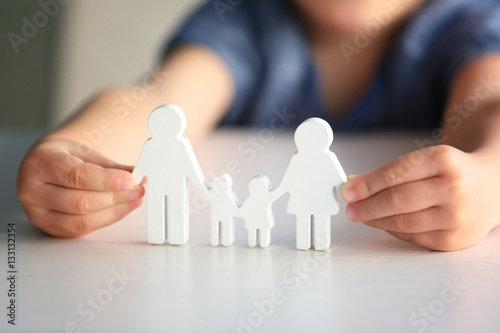 Child holding figure in shape of happy family, closeup. Adoption concept photo