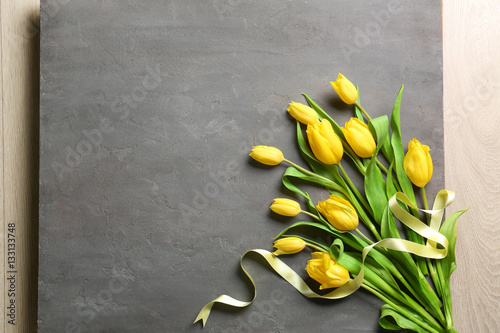 Yellow beautiful tulips with ribbon on gray background