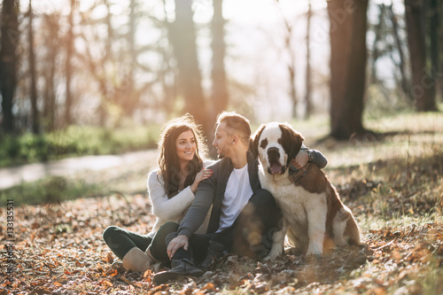 Photography Young couple enjoying nature outdoors together with their adorable Saint Bernard puppy