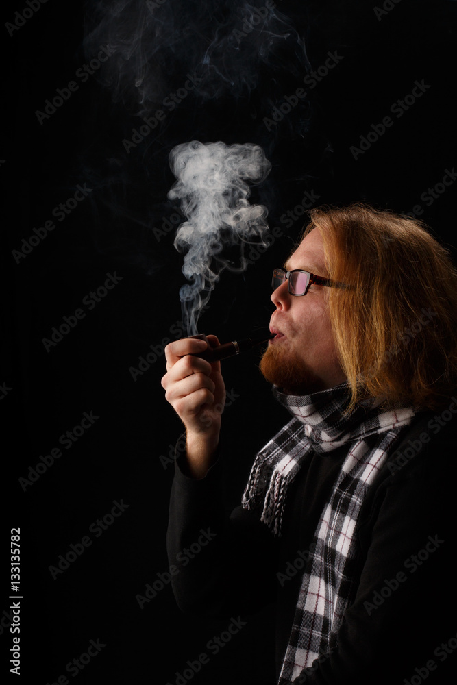 Obraz premium Man with red beard in chequered scarf and glasses holds tobacco