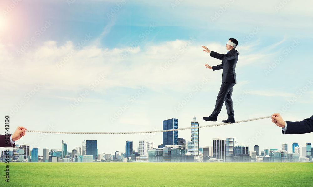 Business concept of risk support and assistance with man balancing on rope Business concept of risk support and assistance with man balancing on rope