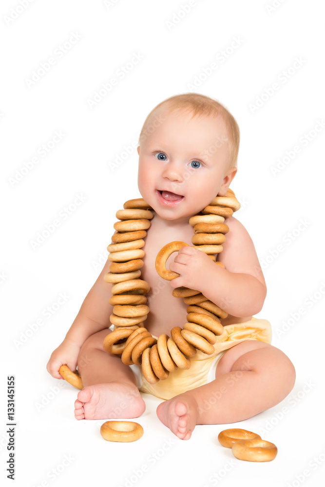 Funny baby sits with bunch of bagels on a white background Funny baby sits with bunch of bagels on a white background
