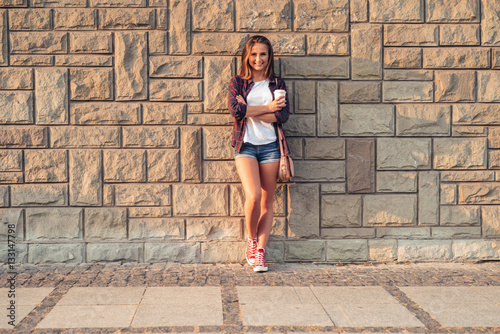Smiling young woman leaning against a wall in the city