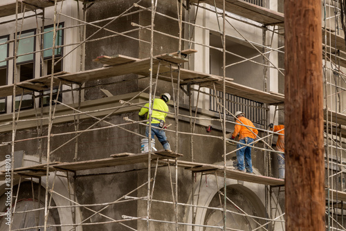 Men in hardhats and safety vests working on a large construction project on a cloudy winter day 