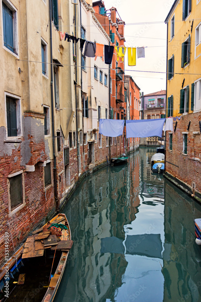 Typical Venice canal with moored boats, colorful buildings and stretched out clothes to dry