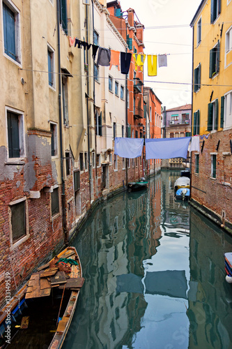 Typical Venice canal with moored boats, colorful buildings and stretched out clothes to dry