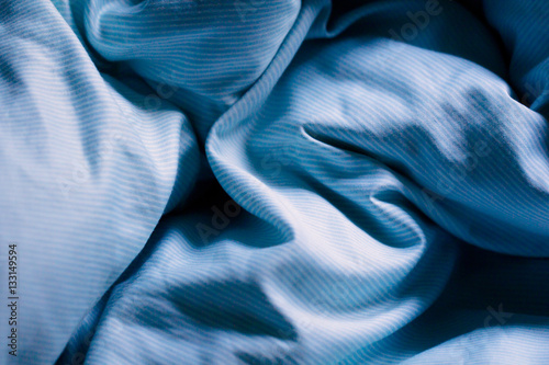 Wrinkled blue bed sheets on a morning as a background