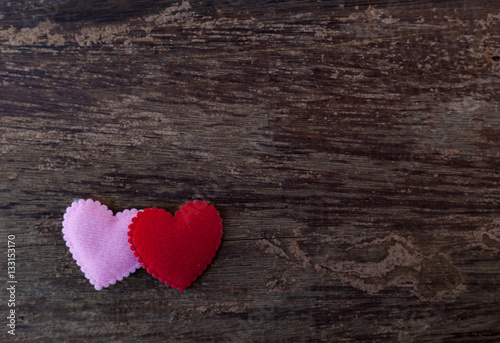 Pink and red hearts placed on the old wooden floor.