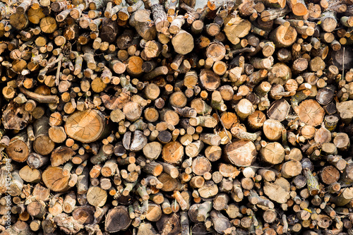 Heap of long wooden logs stacked horizontally