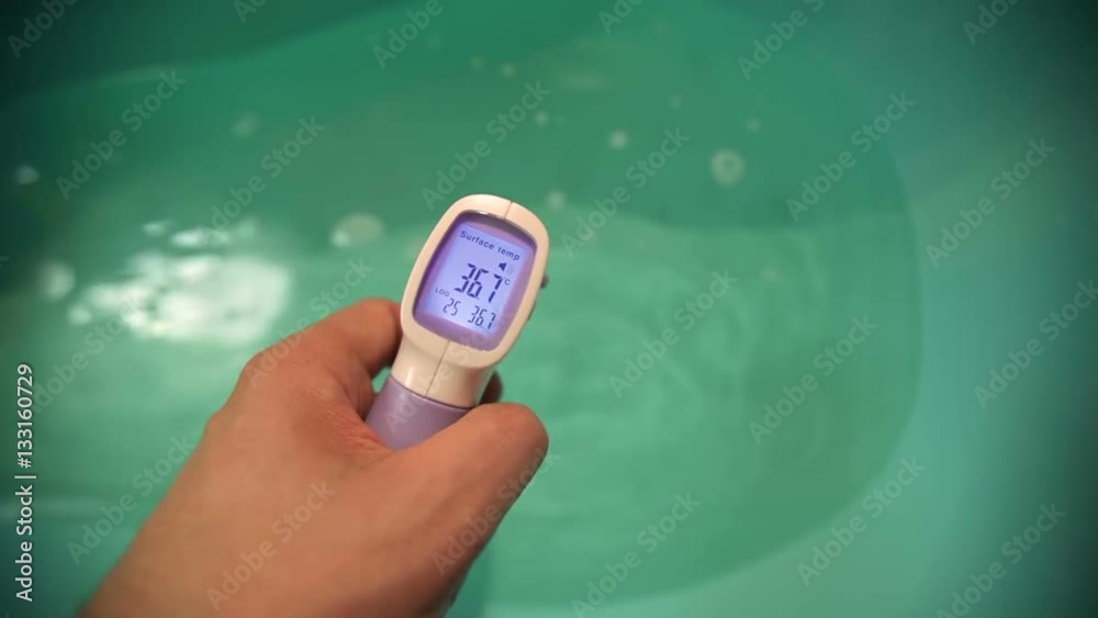 Measuring water temperature in baby bath tub before bathing with