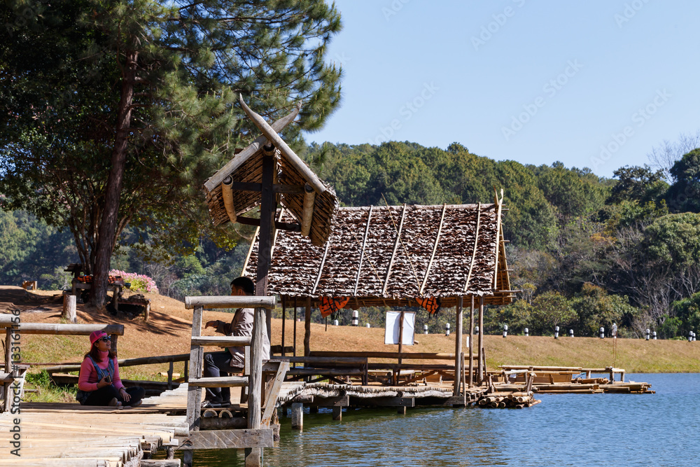 Traveler relaxing on bamboo bridge and hut in lake Traveler relaxing on bamboo bridge and hut in lake