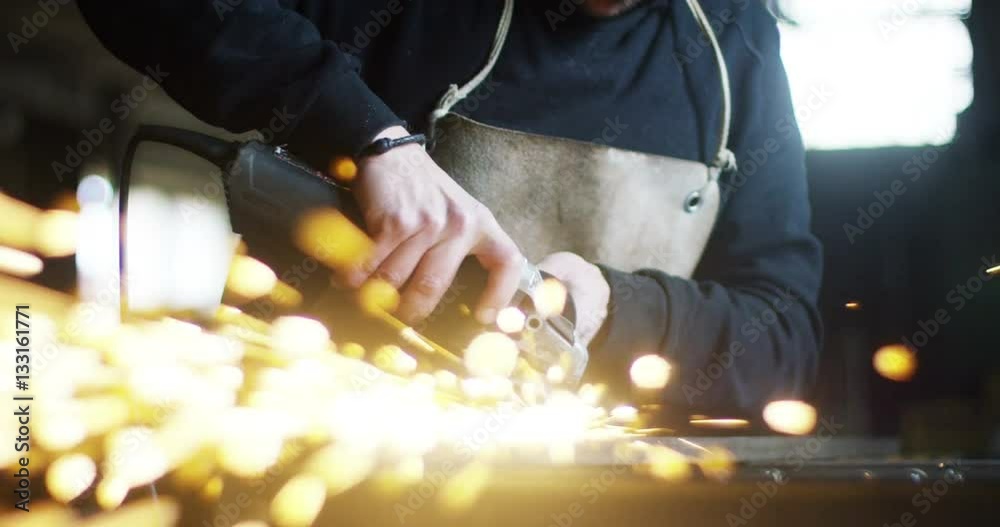 locksmith with a laser cuts in half a sheet of steel causing sparks.The laser heat Nicks iron up to get clean cuts and perfect for buildings with wrought iron.Concept: industry,technology,engineering.