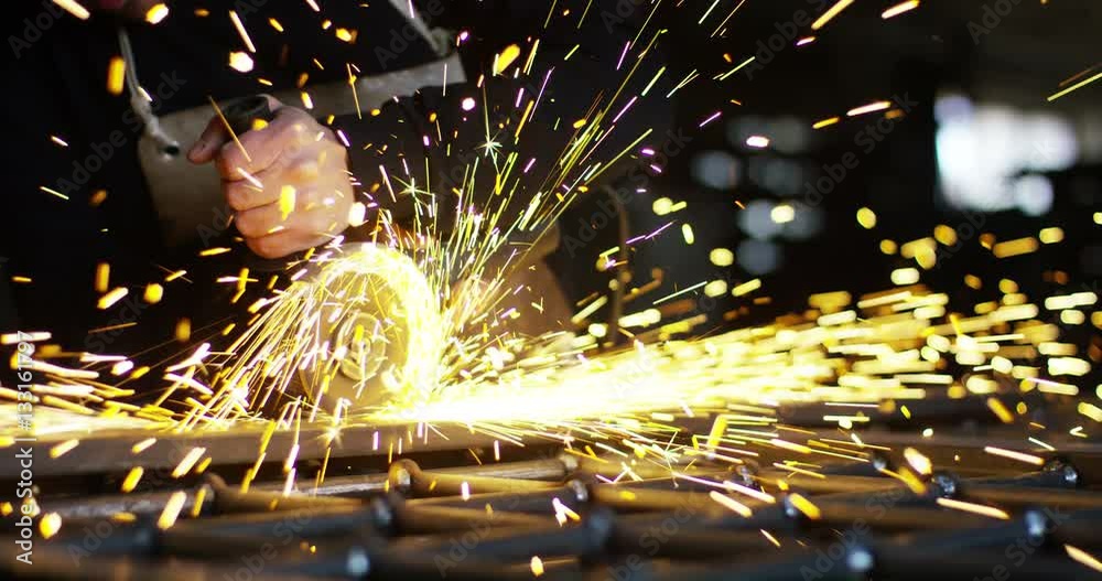 locksmith with a laser cuts in half a sheet of steel causing sparks.The laser heat Nicks iron up to get clean cuts and perfect for buildings with wrought iron.Concept: industry,technology,engineering.