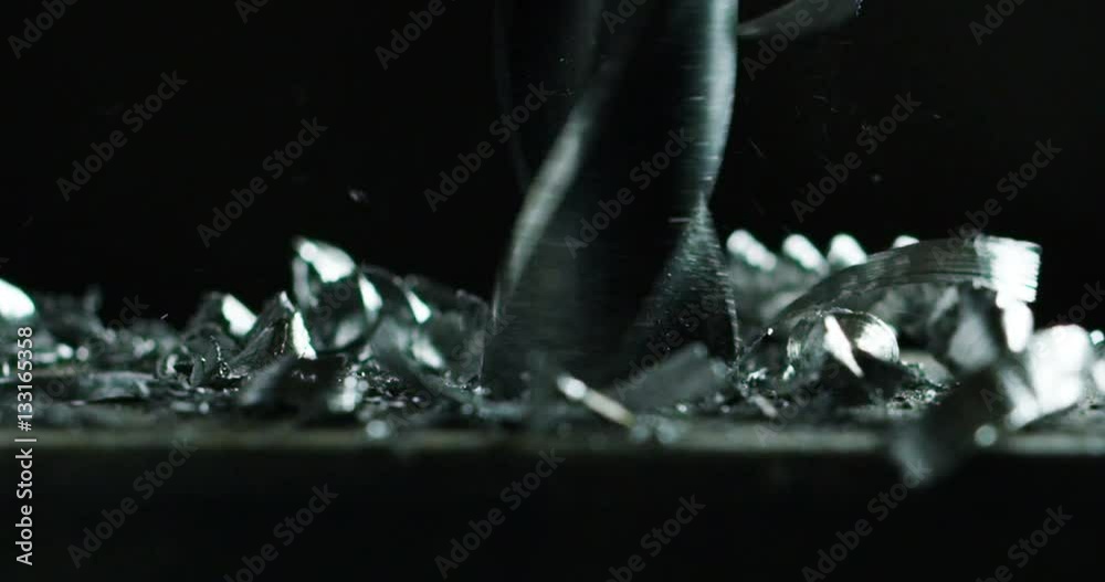 Macro shot of a drill that pierces a sheet of iron or steel. The tip of the metal drill with a circular motion pierces the material. Concept:engineering,industry,technology, locksmith and construction