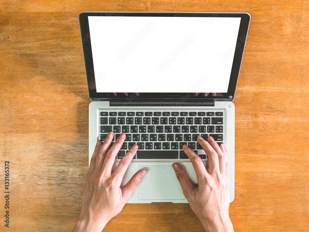 Top view of Male hands using Laptop with blank screen on wooden table Top view of Male hands using Laptop with blank screen on wooden table