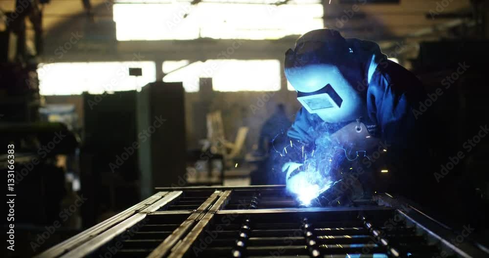 .A blacksmith or welder, with his welder, welding steel and iron, in extreme slow motion. The welder uses a mask to protect your eyes from sparks. concept: manual work, blacksmith, industry, welder