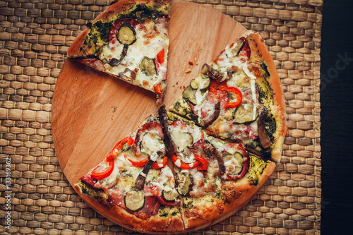 Delicious pizza with salami, cheese, peppers and meat, cut into