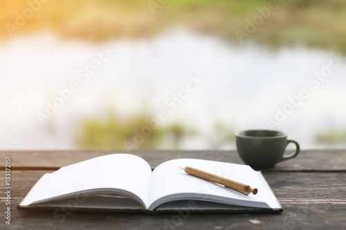 Stock Photo:.open book with pencil and office cup on a wooden ta