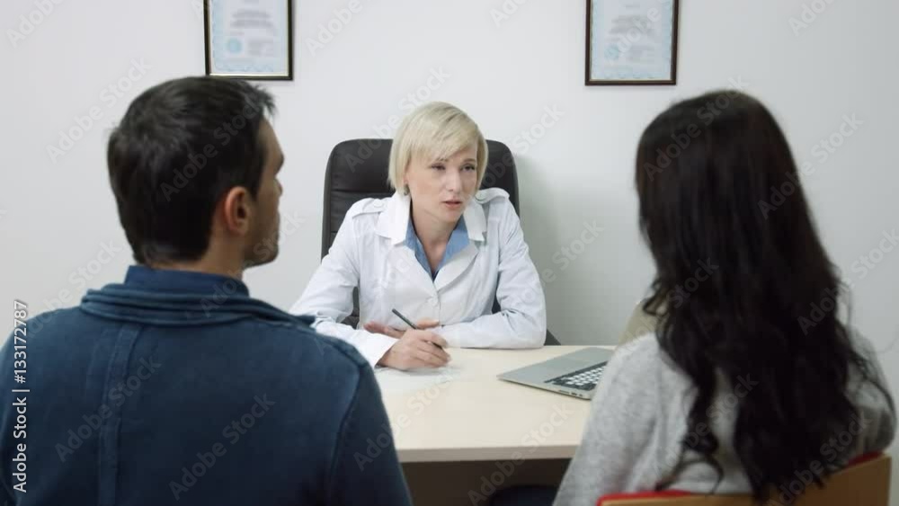Female doctor consults couple at her office, Young family visiting a doctor. Female doctor consults couple at her office, Young family visiting a doctor.