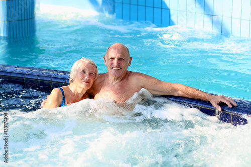 Happy healthy senior couple having fun together in the swimming pool enjoying jacuzzi