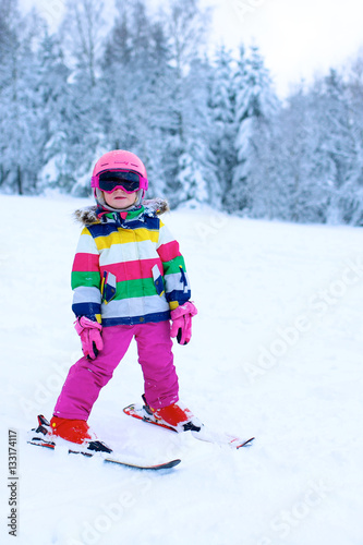 Happy child enjoying vacation in Alpine resort in Austria. Little girl skiing in mountains. Active sportive toddler learning to ski. Winter sport for family. Skier racing in snow.