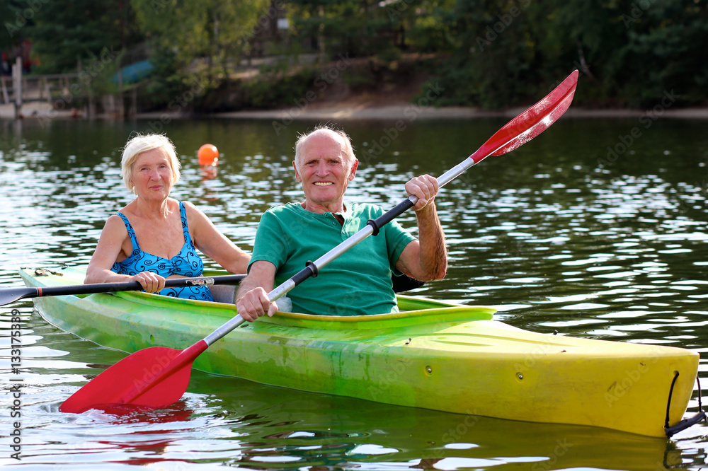 Senior couple kayaking on the river. Healthy elders enjoying summer day outdoors. Sportive people having fun at the nature. Active retirement concept.