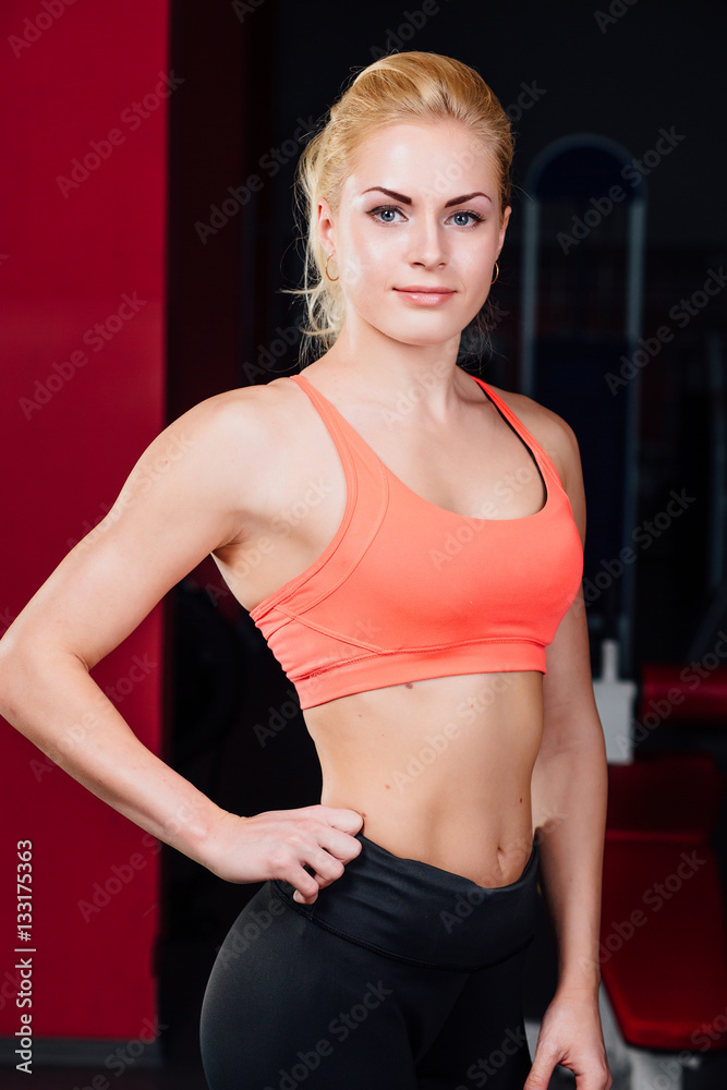 Portrait of smiling sporty woman standing. Posing on a dark background Portrait of smiling sporty woman standing. Posing on a dark background