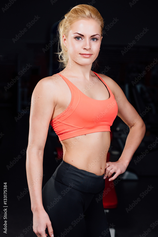 Portrait of smiling sporty woman standing. Posing on a dark background