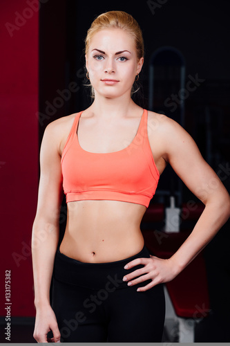 Portrait of smiling sporty woman standing. Posing on a dark background