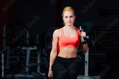sexy girl doing exercises in her arms biceps and triceps. fitness with dumbbells in the gym.