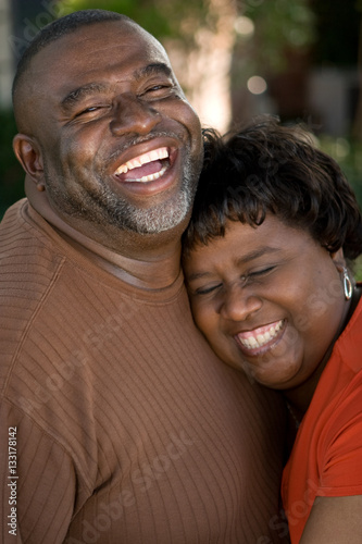 Mature African American couple laughing and hugging.