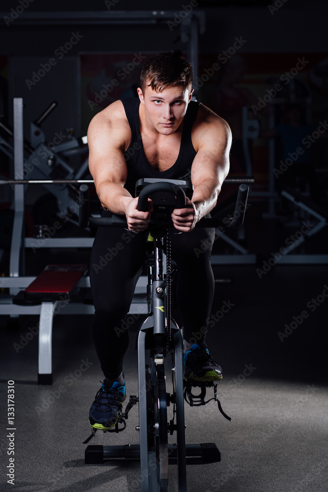 Portrait of a handsome man workout on fitness the exercise bike dark at gym. Portrait of a handsome man workout on fitness the exercise bike dark at gym.