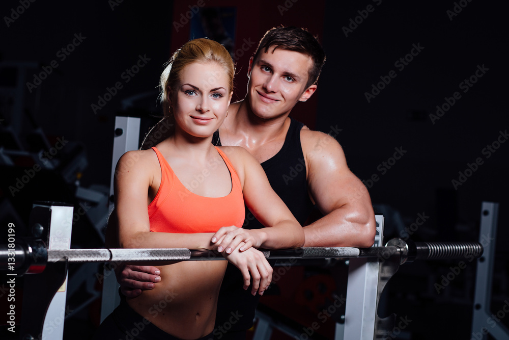 Athletic couple - man and woman Rest between exercises near the barbell in gym