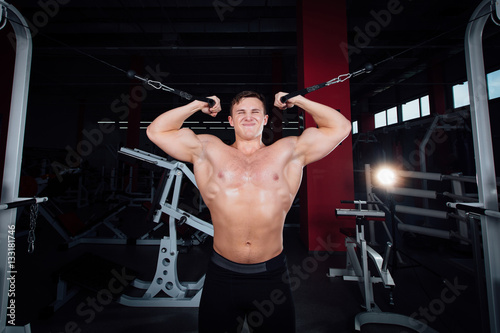 big strong bodybuider without shirts demonstrate crossover exercises. The pectoral muscles and hard training