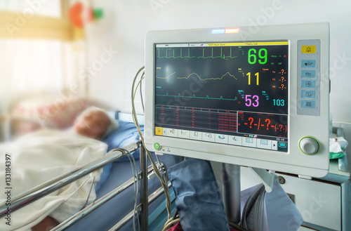     Close up  digital device for measuring blood pressure monitor with elderly patient sleep on the bed in hospital ward room photo