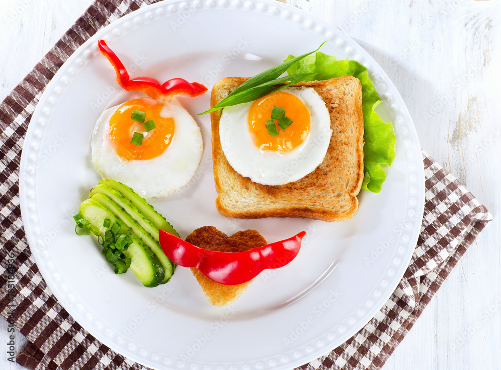 Fried eggs with toast and fresh vegetables for a breakfast.
