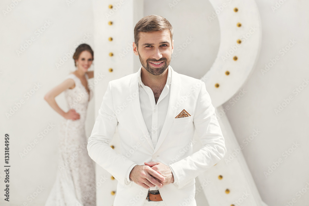 Chic wedding couple groom and bride posing in a white Studio. Ha Chic wedding couple groom and bride posing in a white Studio. Ha