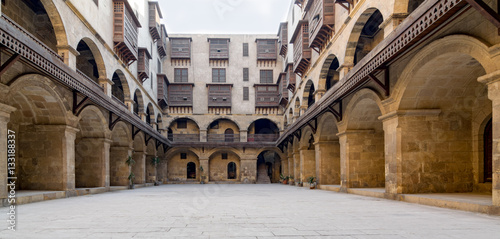Facade of caravansary (Wikala) of Bazaraa, with vaulted arcades and windows covered by interleaved wooden grids (mashrabiyya), suited in Tombakshia street, Al Gamalia district, Medieval Cairo, Egypt photo