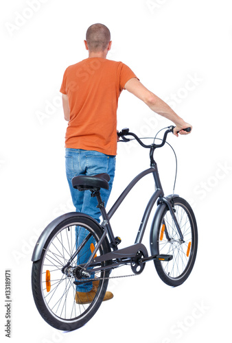 back view of a man with a bicycle. Cyclist keeps the wheel of a bicycle. Rear view people collection. backside view of person. Isolated over white background. The guy in a T-shirt is a bicycle.