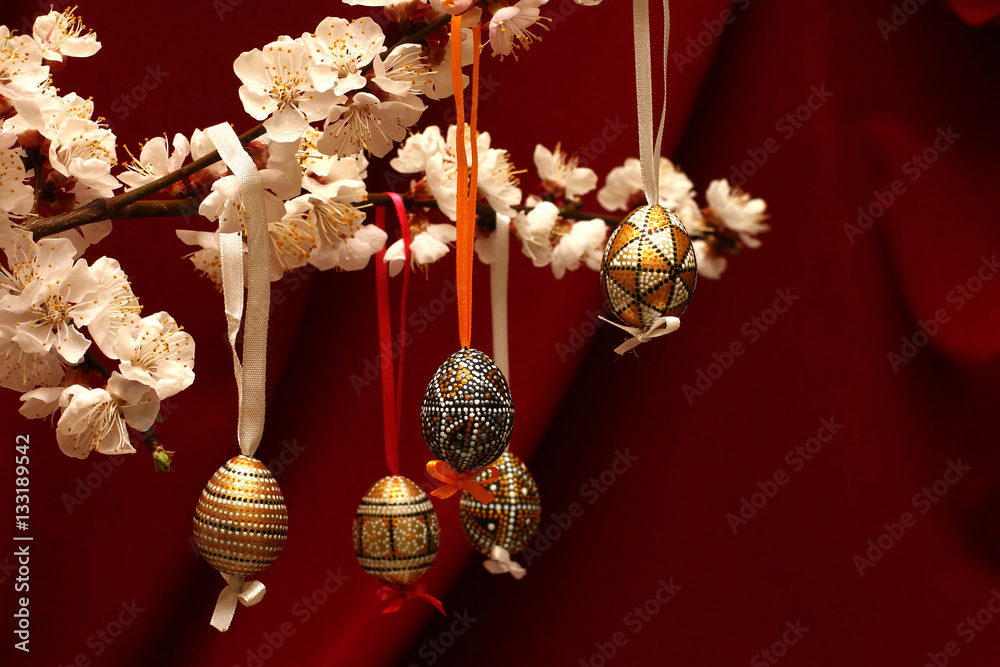 Easter eggs on flowering tree branch. Template for congratulations card with red cloth background.