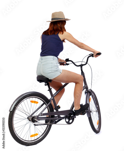 back view of a woman with a bicycle. cyclist sits on the bike. Rear view people collection.  backside view of person. Isolated over white background. Beautiful girl in a hat and shorts on a bike.