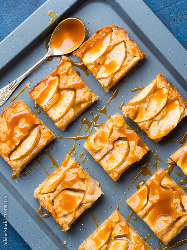 Home made apple cinnamon blondies with salted caramel. Sweet food home made dessert treat. Dark blue background flat lay