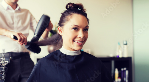 happy woman with stylist making hairdo at salon
