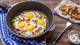 Fried eggs in pan with tomatoes and green fresh onion.