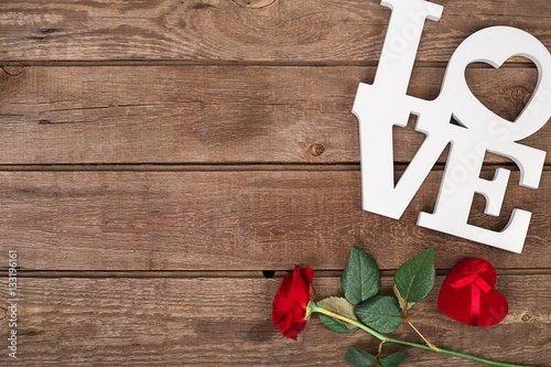 Red rose and box over wooden background