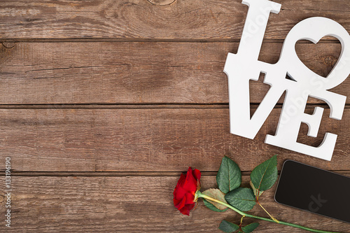 Red rose and smart over wooden background