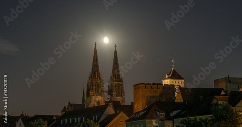 Nachtaufnahme von Regensburg mit Mond direkt über dem Dom