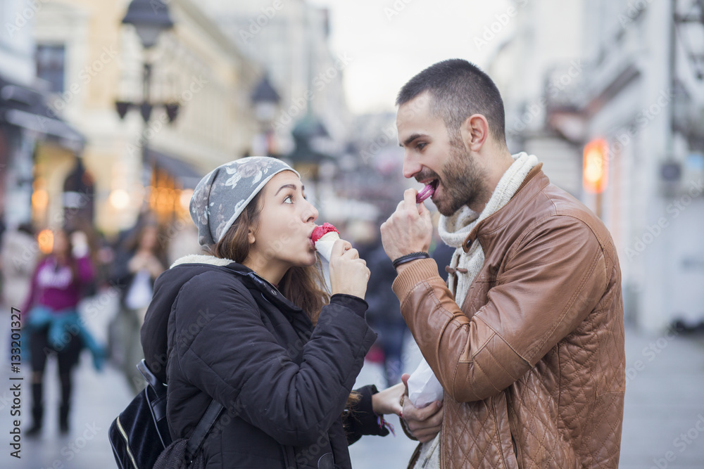 Fototapeta premium Young couple in love in the city walks eating ice cream on stree