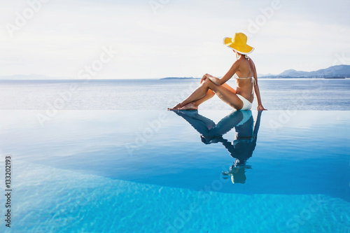 Young woman enjoying a sun in the infinity pool. Vacations, summer fun, enjoy life, travel lifestyle, sunbathing concept